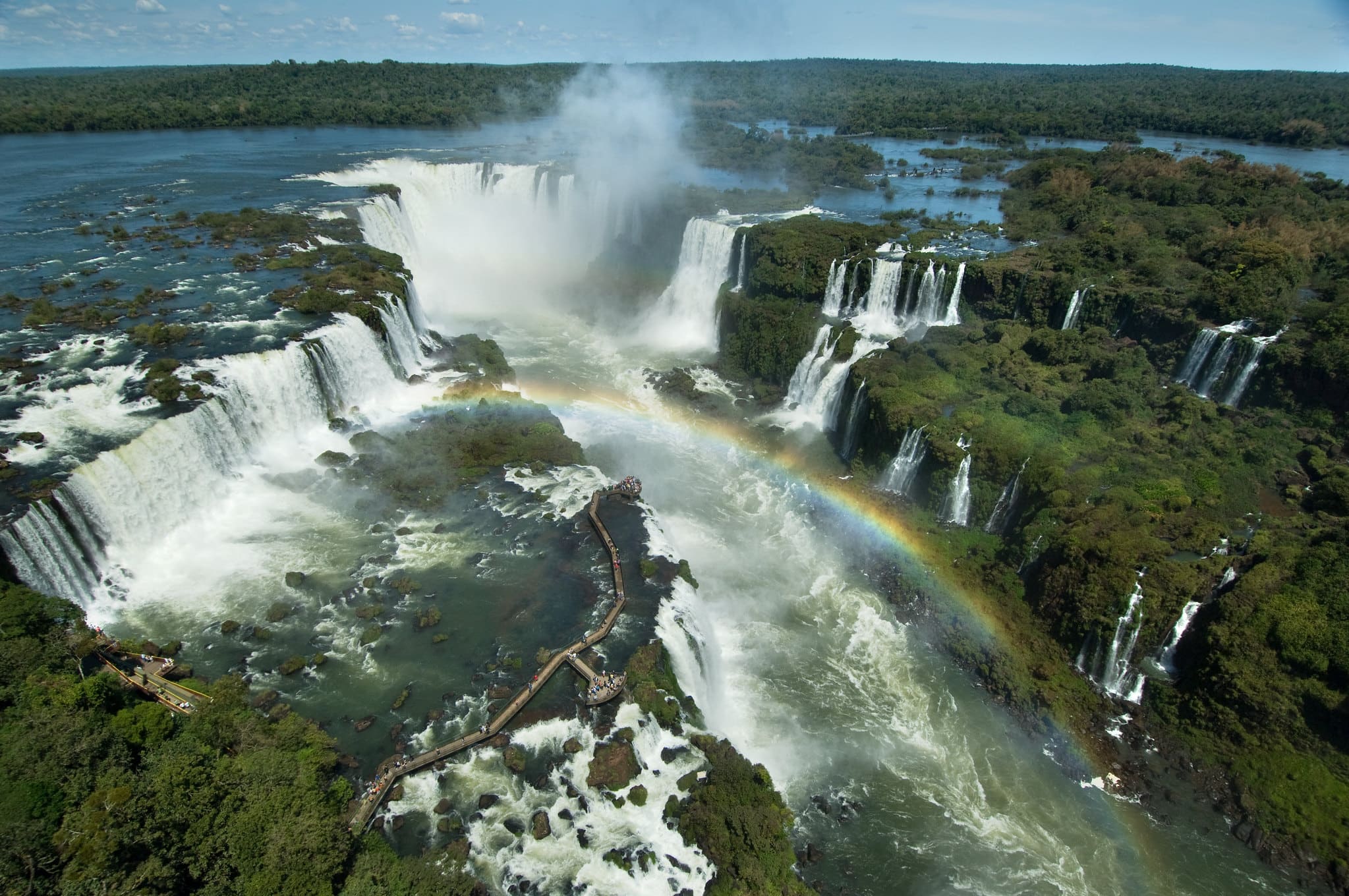 Vista das quedas d'agua em um dia ensolarado e um arco-íris